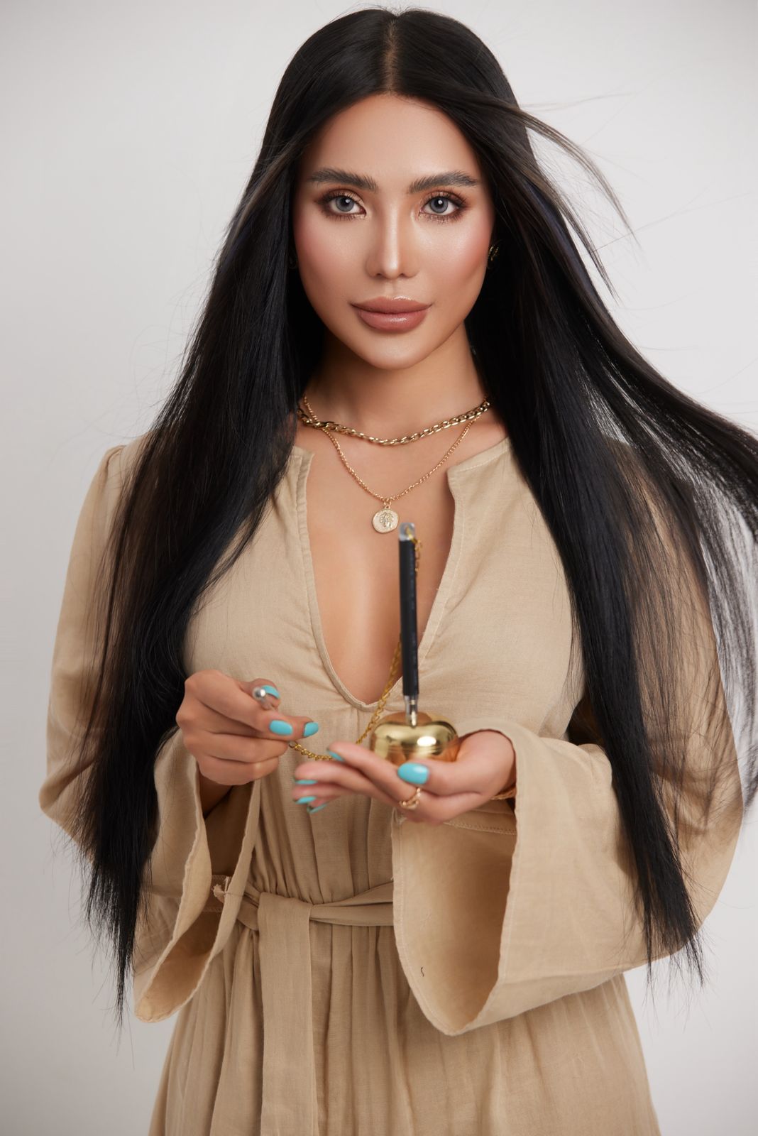 Woman with long dark hair holding a small gold ritual vessel